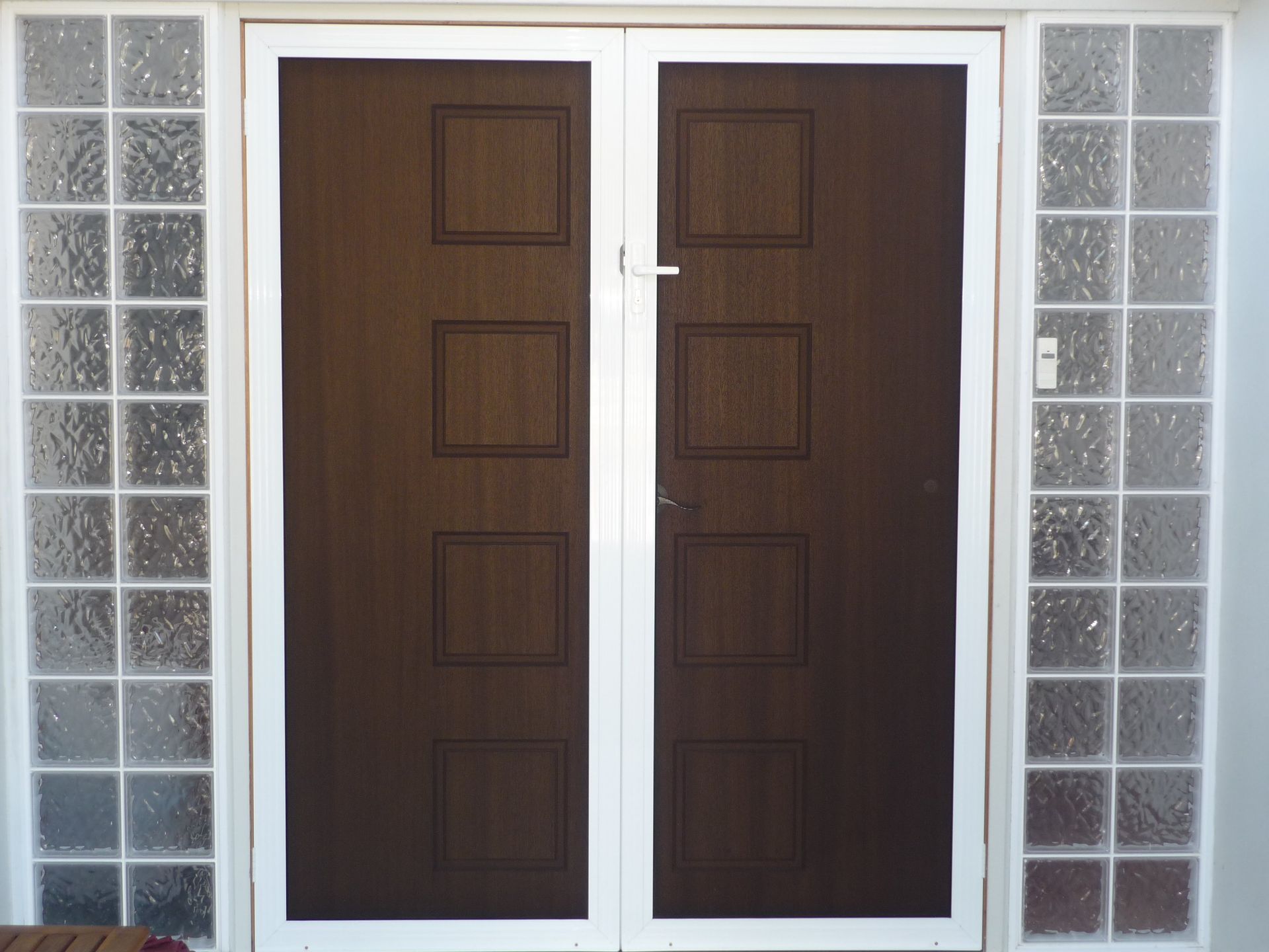 A brown door with a white frame is surrounded by glass blocks.