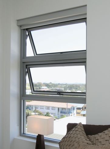 A living room with a couch and a window with a view of a city.