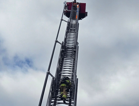 A fire fighter climbing an aerial ladder.