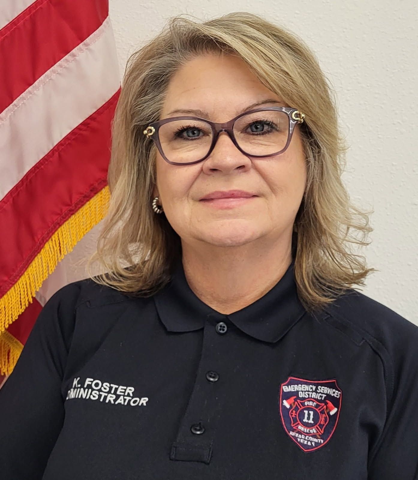A woman wearing glasses and a blue shirt is smiling for the camera.