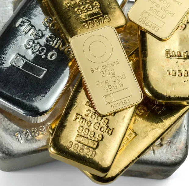 Close-up of gold and silver bullion bars with stamped markings.