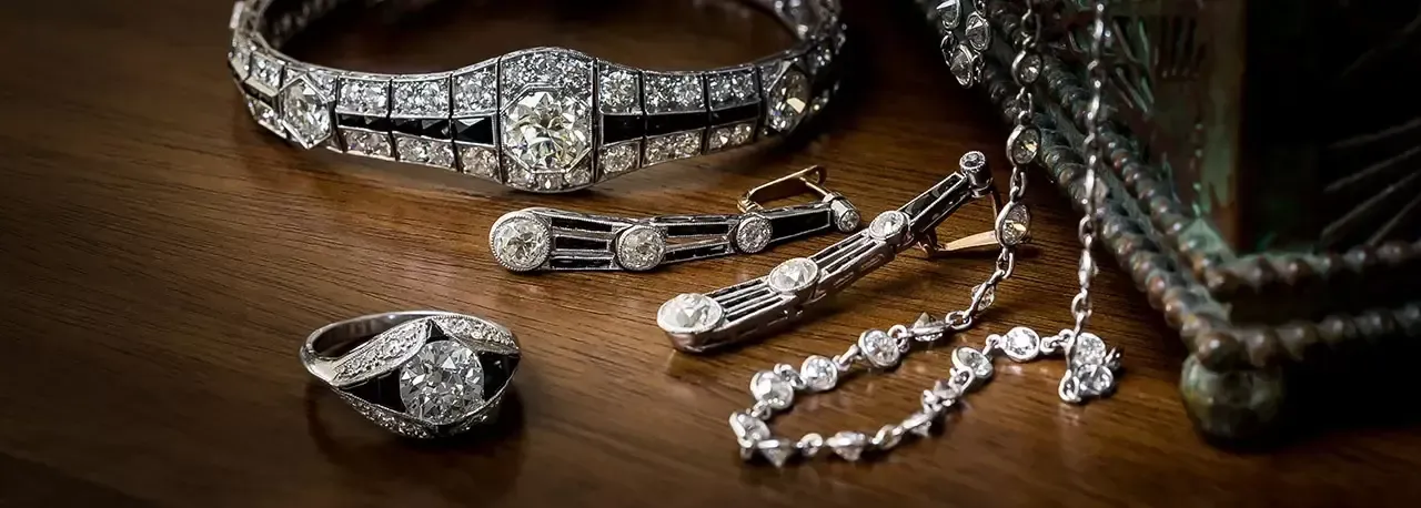 Close-up of diamond jewelry including a bracelet, earrings, necklace, and ring on a wooden surface.