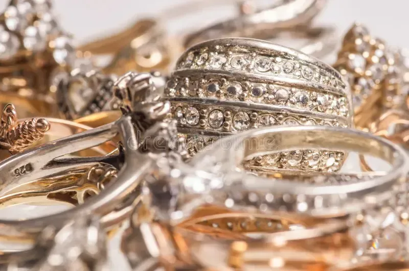 Close-up of a pile of various gold and silver rings, some with embedded diamonds.
