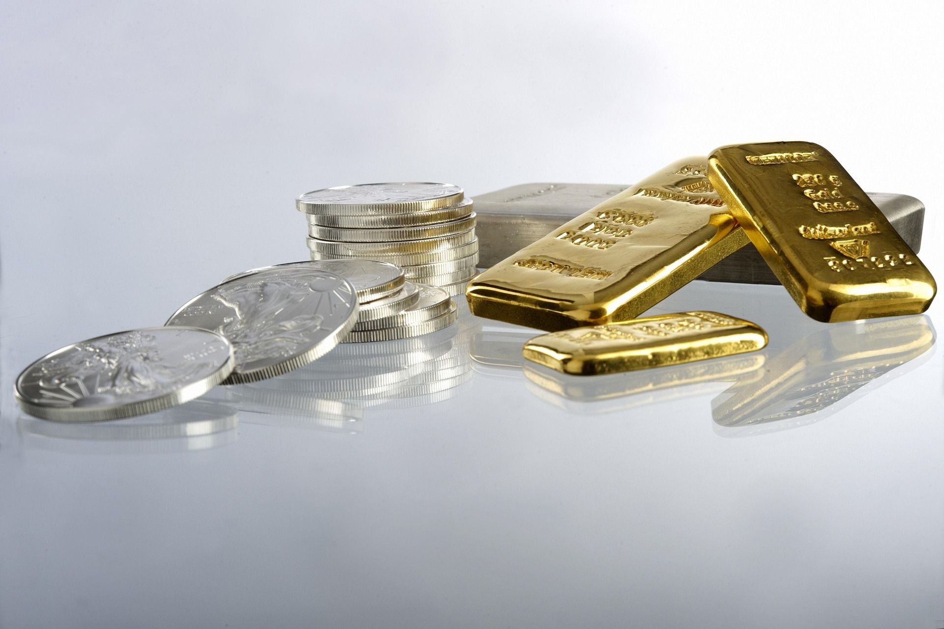 Gold bullion bars and coins arranged on a dark surface