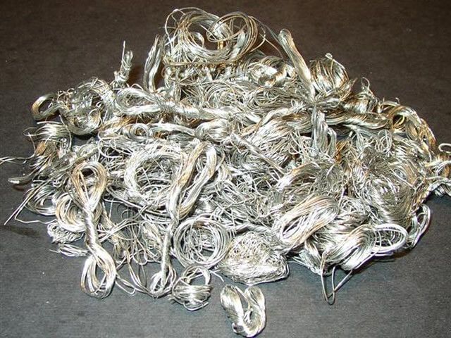 Pile of silver-colored, tangled wires on a dark surface.