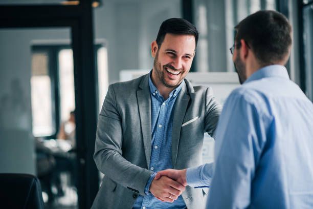 Two men shaking hands, one smiling in a business office.