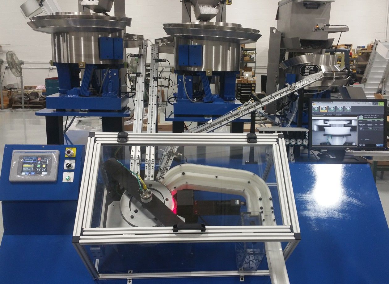 An overhead view of industrial machinery with two black cameras mounted in the foreground and blue lights in the center.