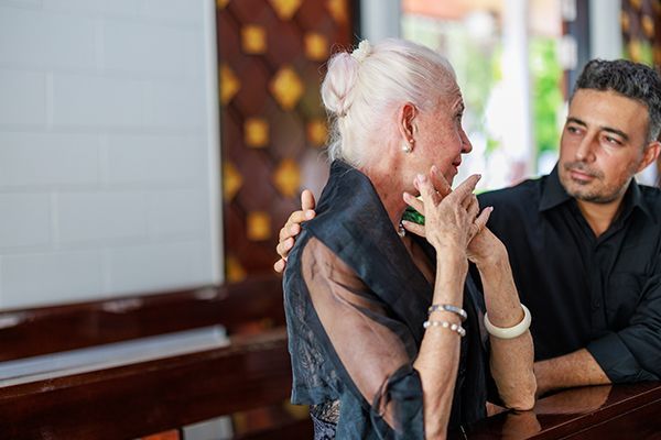 A senior woman and her son participate in a funeral ceremony at a Catholic church