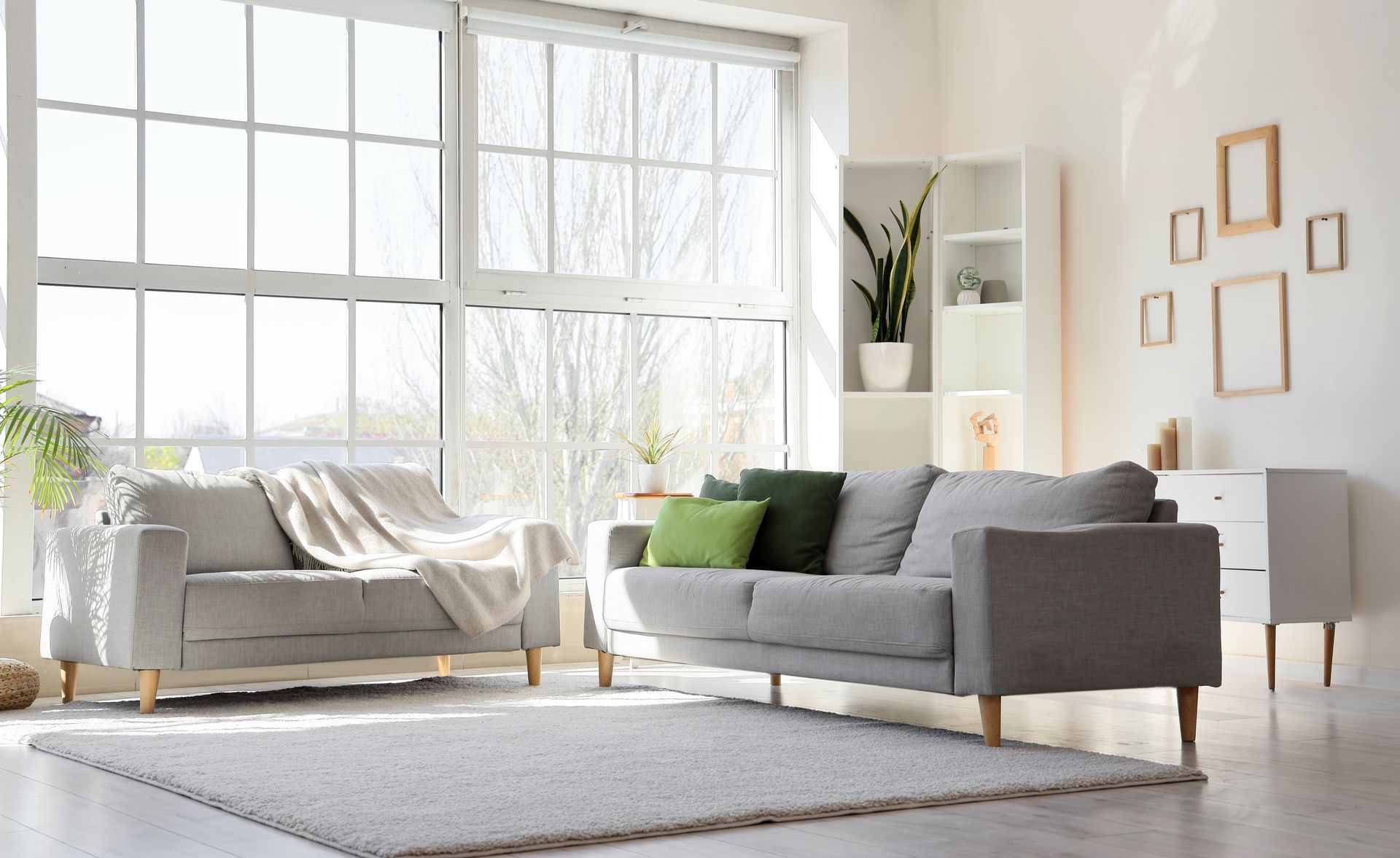 A living room with two couches, a rug, and a large window.