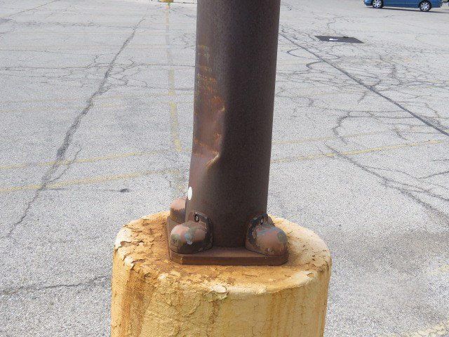 Outdoor light pol that has rust on the metal where it attaches to the concrete base