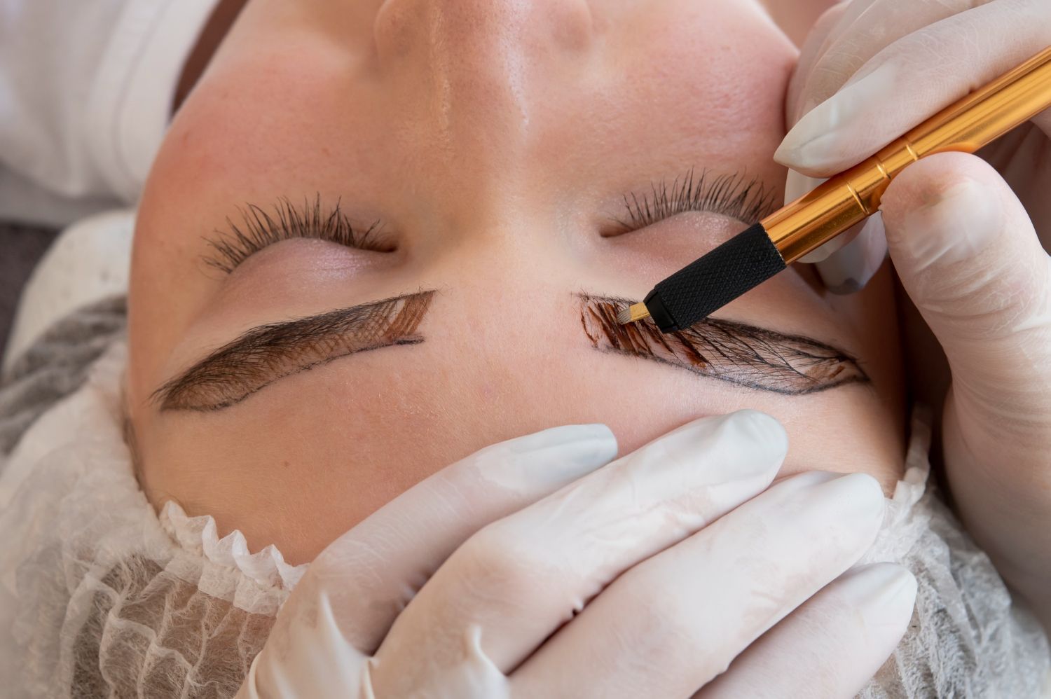 A woman is getting permanent makeup on her eyebrows.