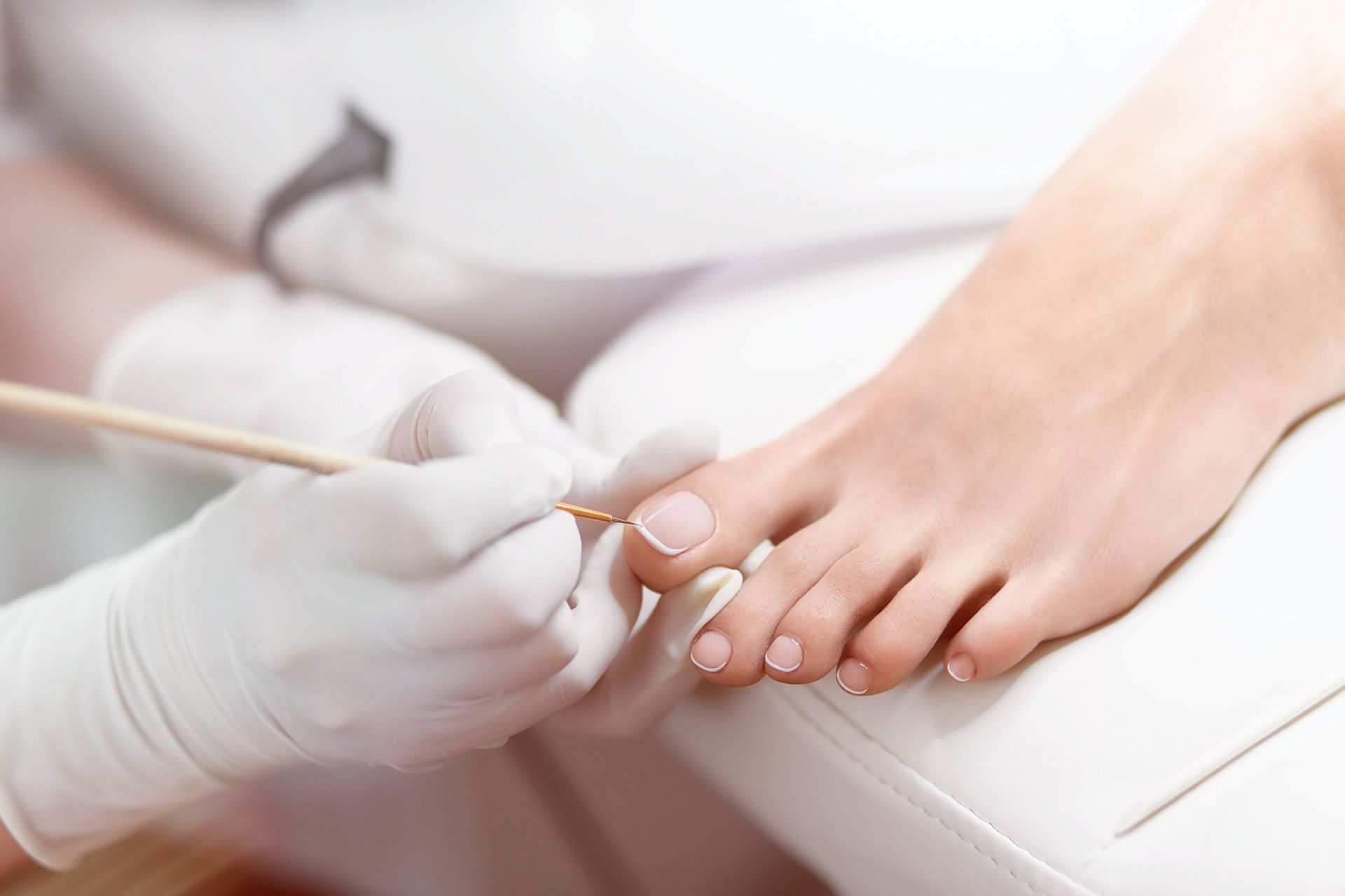 A woman is getting her toenails painted by a nail artist.