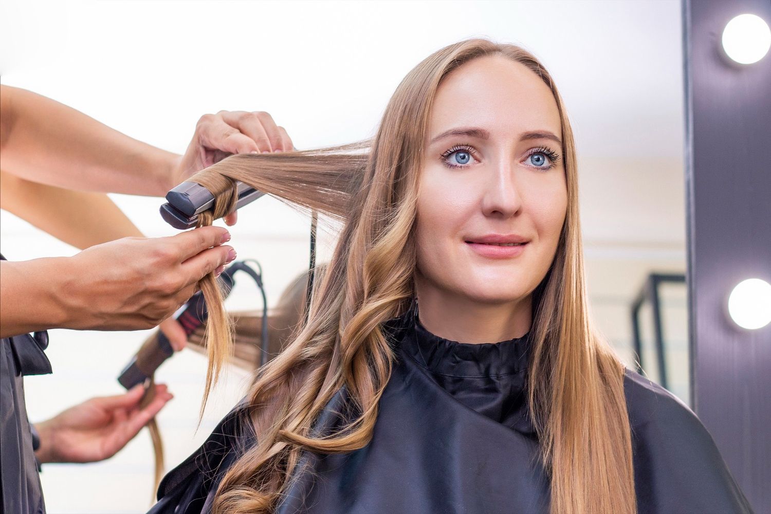 A woman is getting her hair straightened at a hair salon.