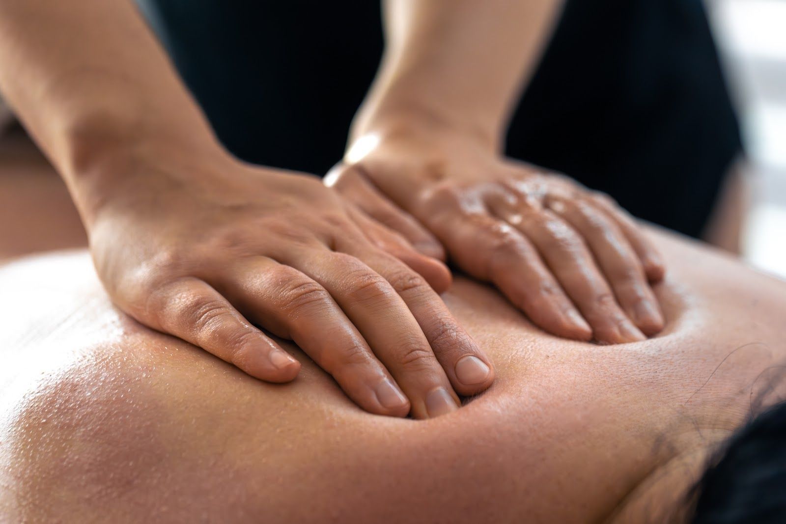 Hands giving a back massage; skin appears oiled.