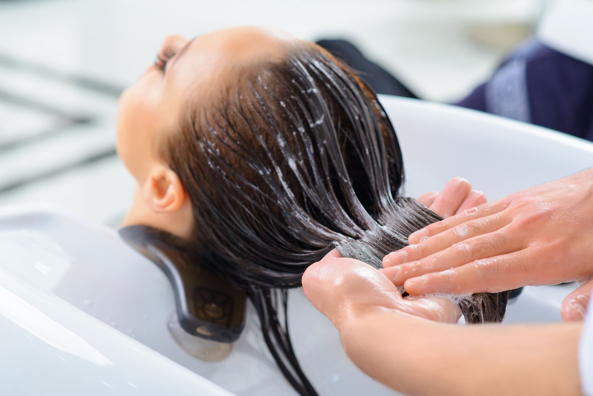 A woman is getting her hair washed in a sink at a salon.