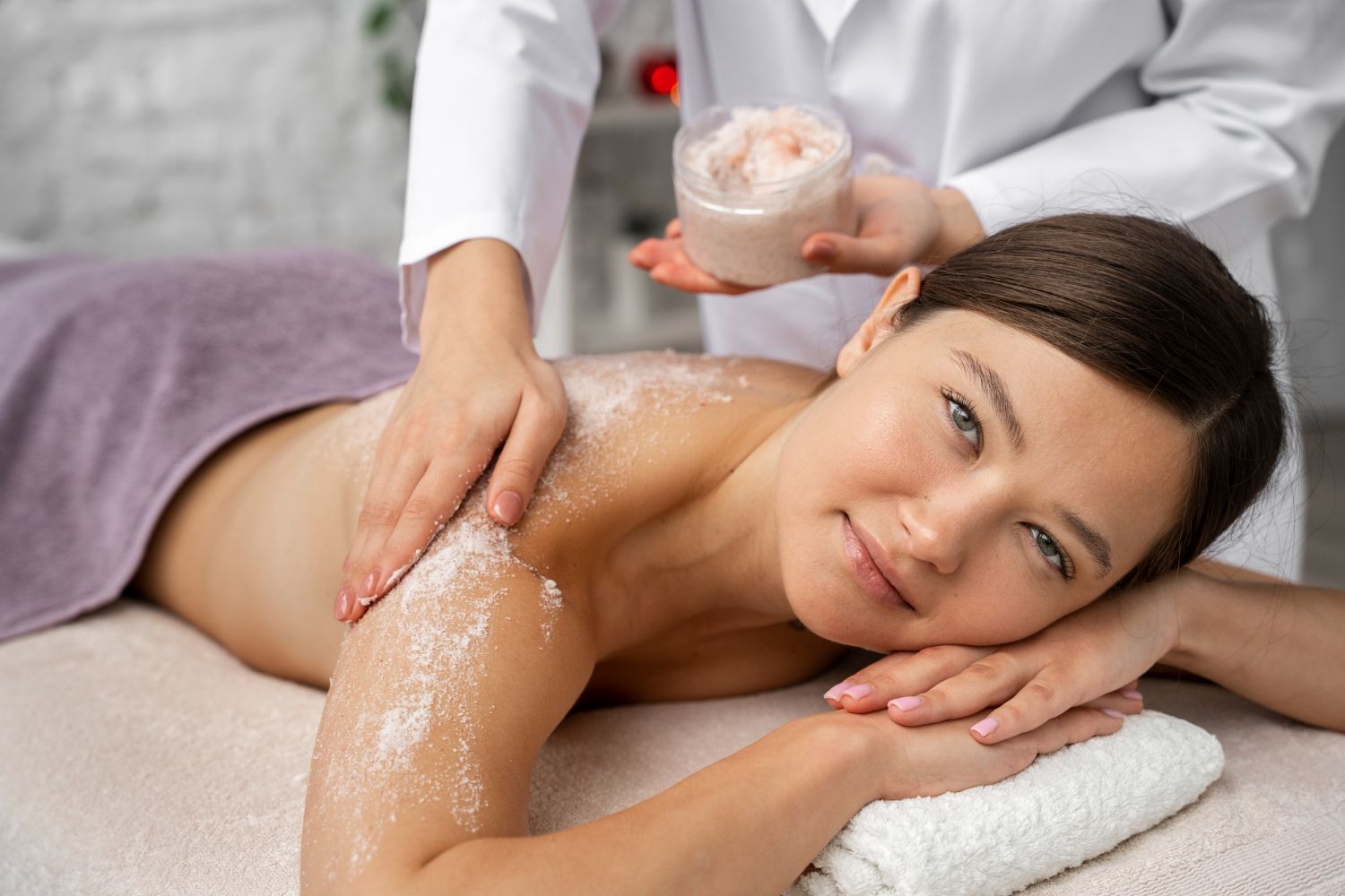 A woman is getting a body scrub at a spa.