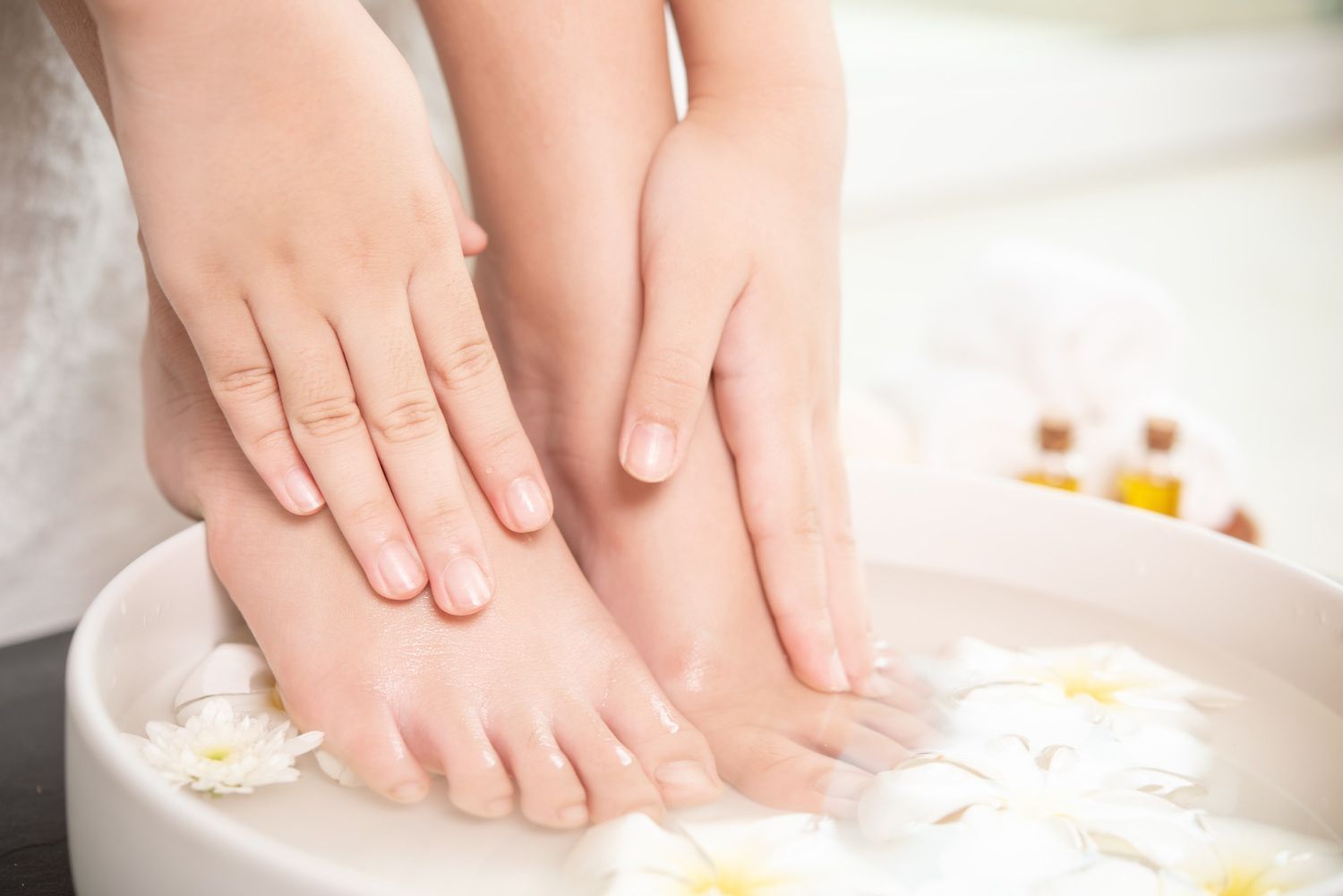 A woman is washing her feet in a bowl of water with flowers.