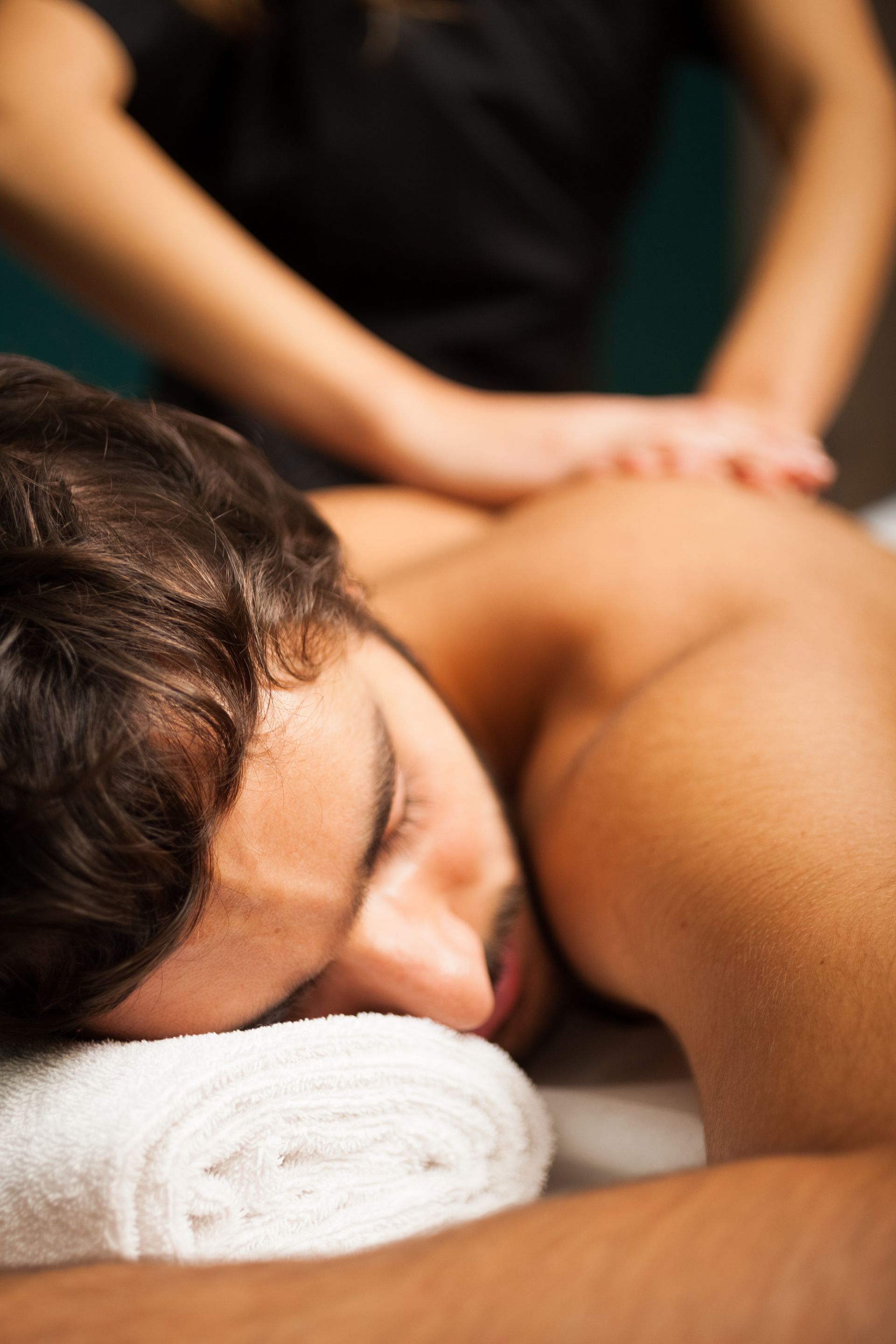 A man is laying on a table getting a massage from a woman.