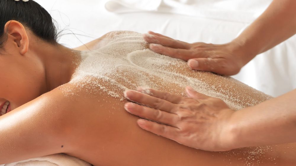 A woman is getting a massage with sea salt on her back.