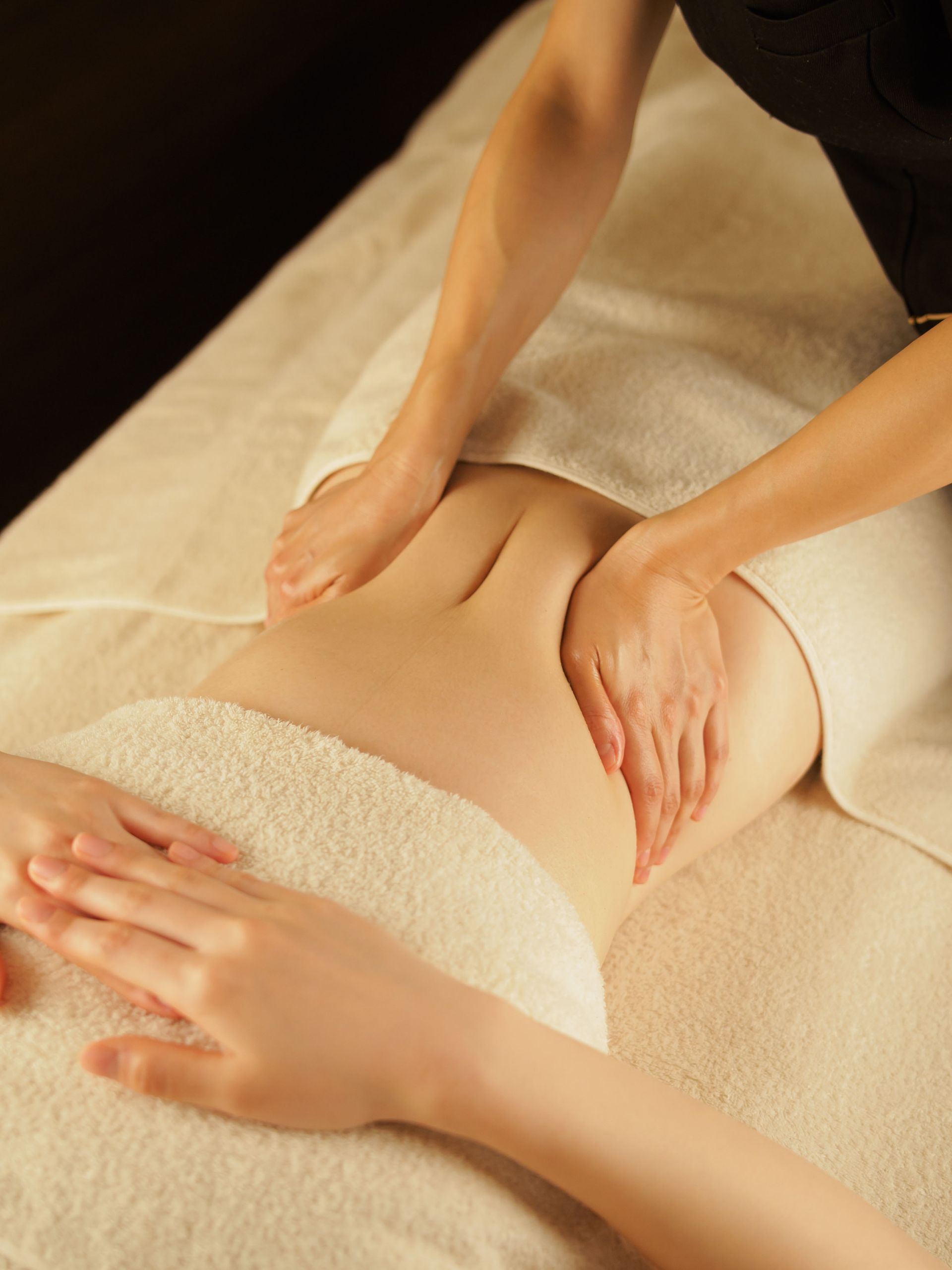 A woman is getting a massage on her stomach while wrapped in a towel.