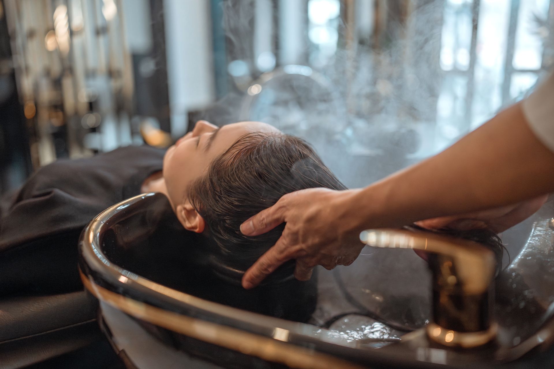 A woman is getting her hair washed in a sink at a salon.