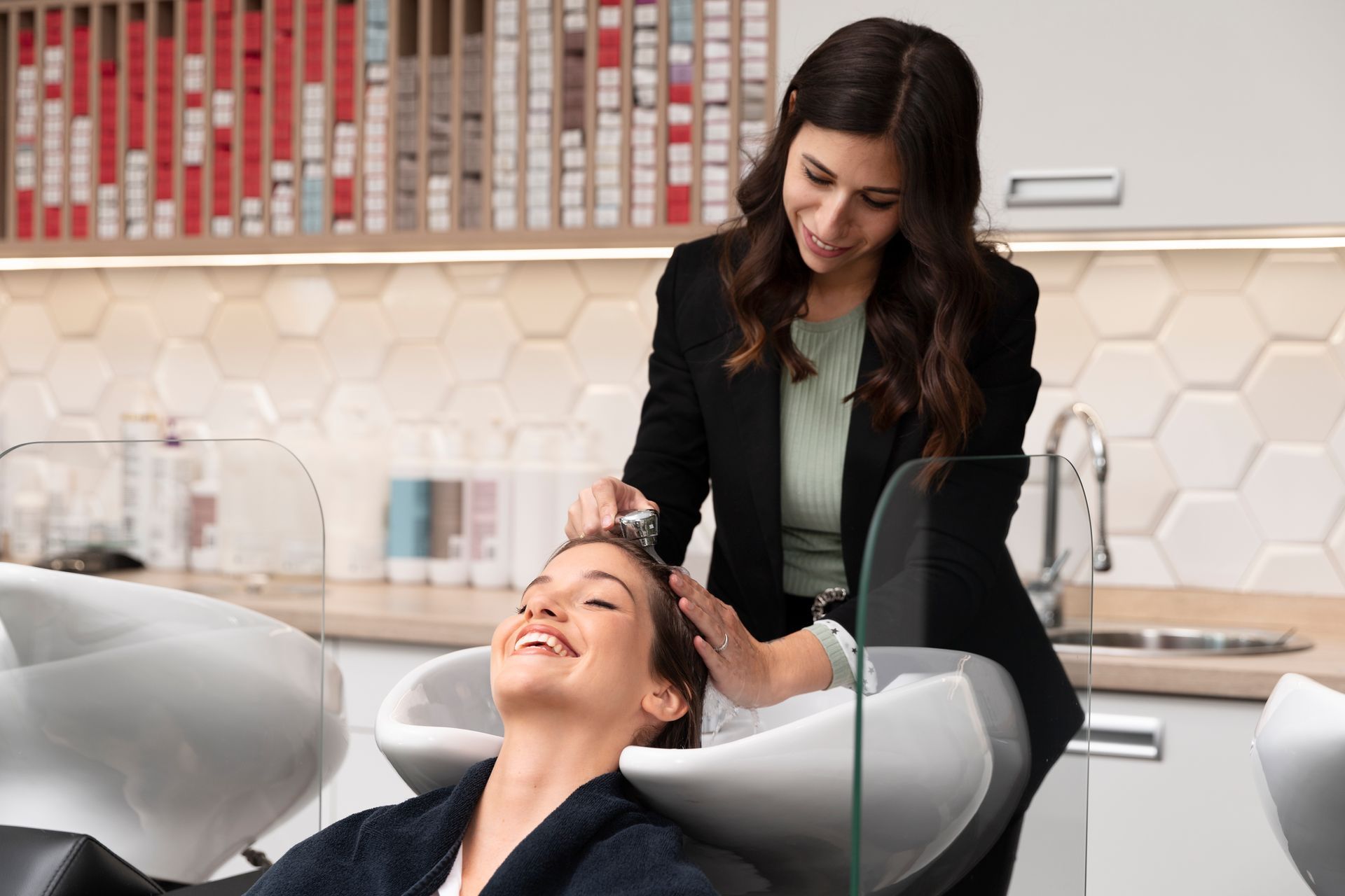 A woman is getting her hair washed by a hairdresser in a salon.