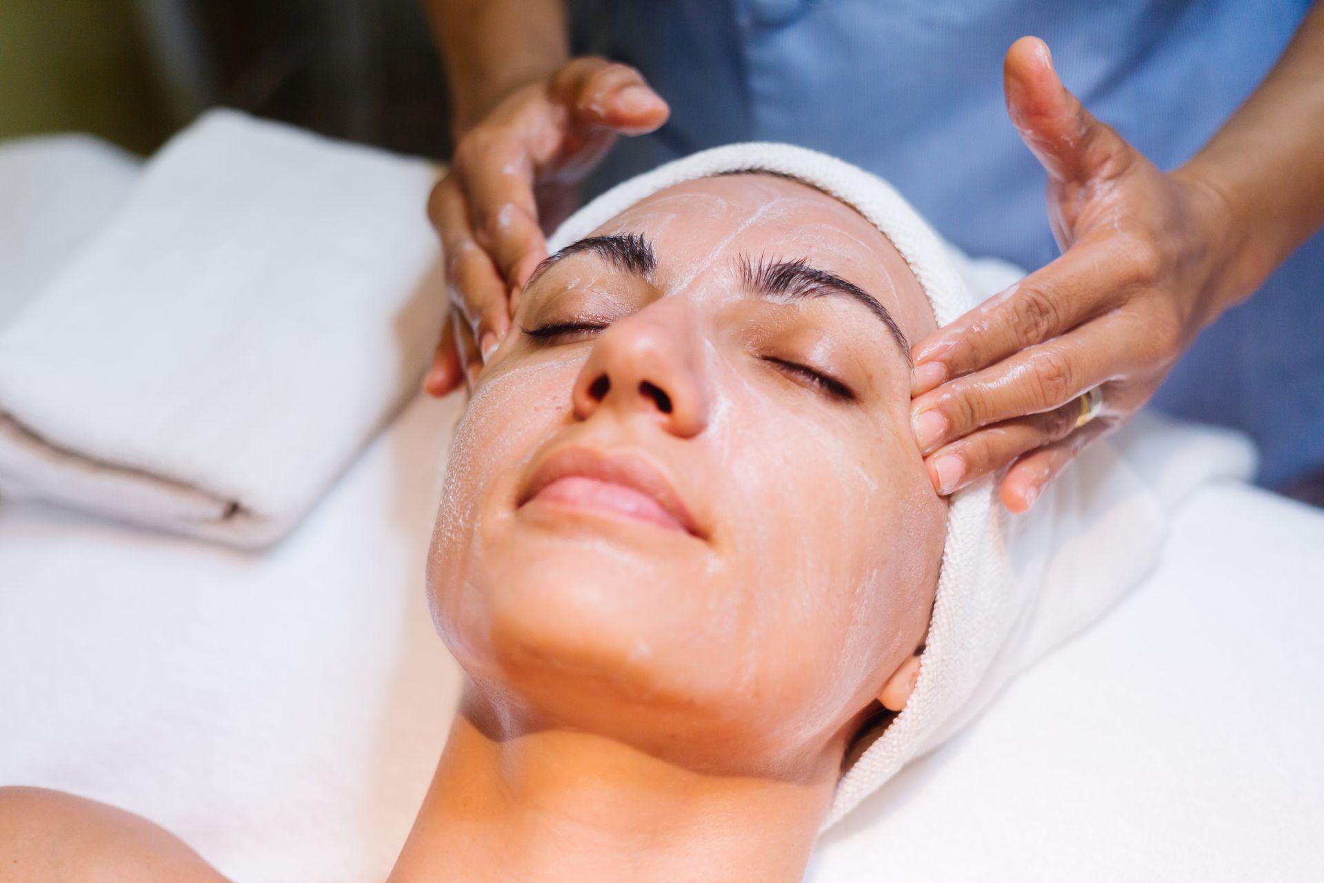 A woman is getting a facial massage at a spa.