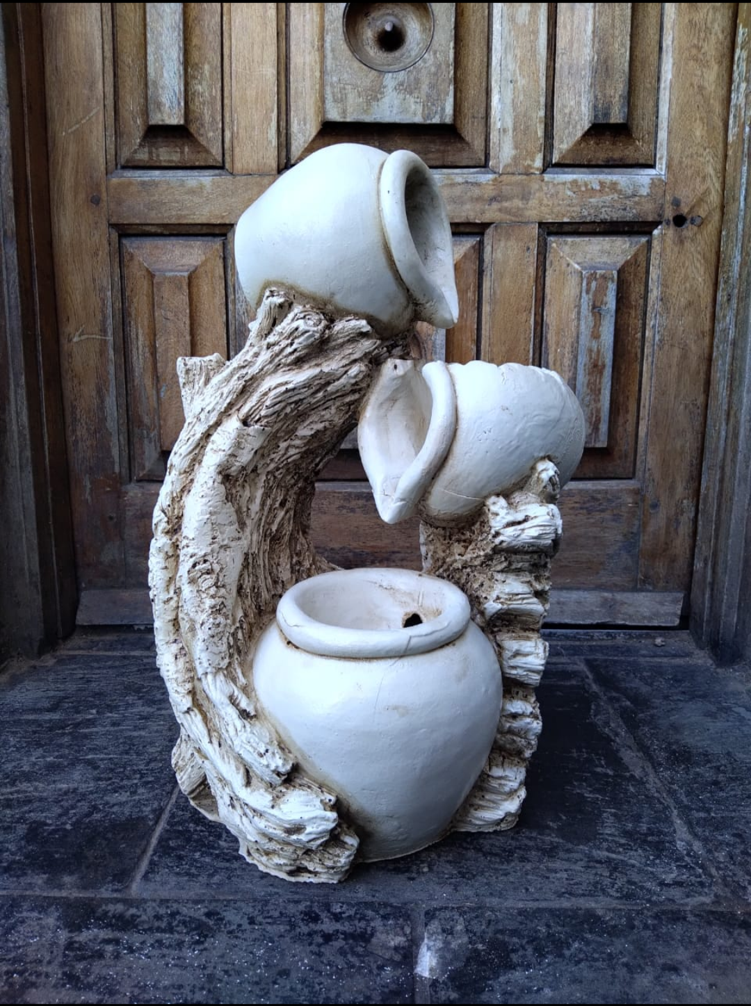 Una estatua de una fuente con una puerta de madera al fondo.