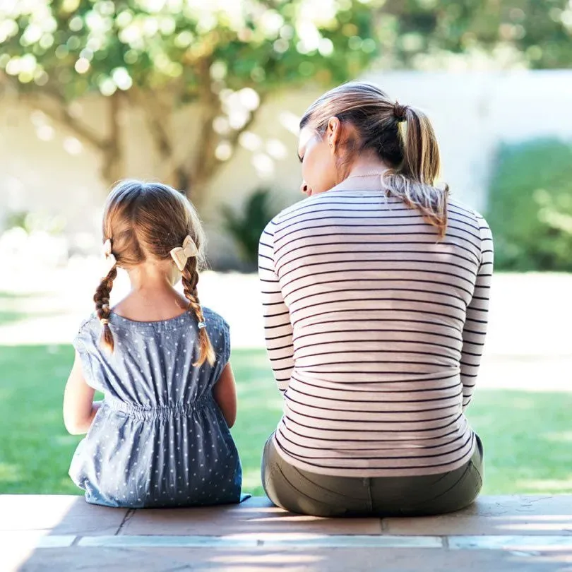 a woman and a little girl are sitting on a bench