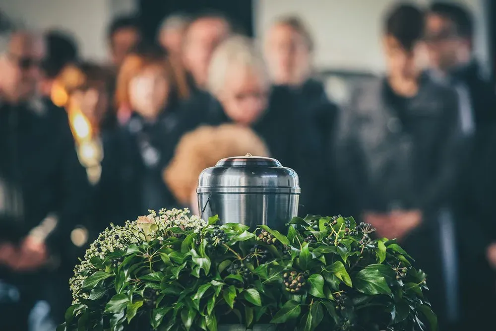 a silver urn with a funeral in the background
