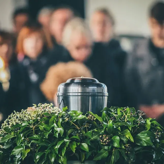 a metal urn is sitting on top of a wreath of green leaves .