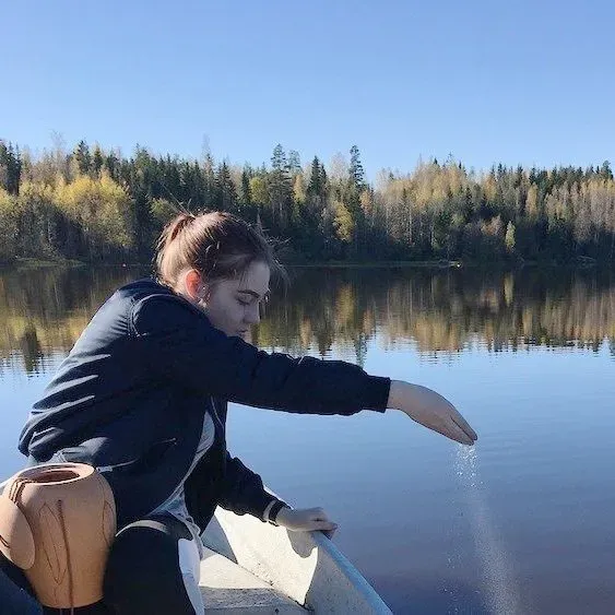 a woman is sitting in a boat on a lake .