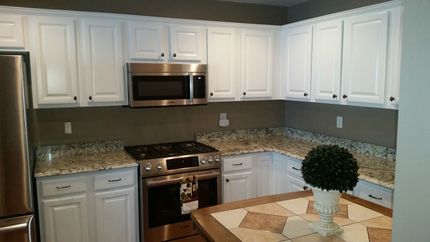 Modern kitchen with white cabinets, granite countertops, stainless steel appliances, and a small dining table