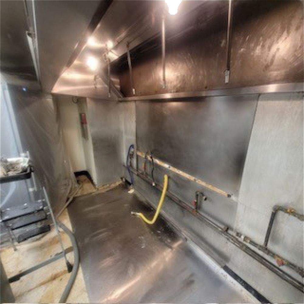 Stainless steel kitchen, vent hood, work surface, and piping.