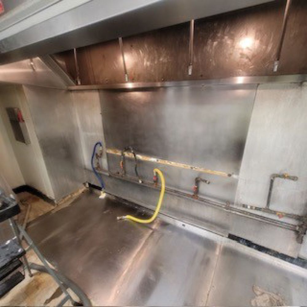 Person vacuums dust from an air vent with a red vacuum cleaner.