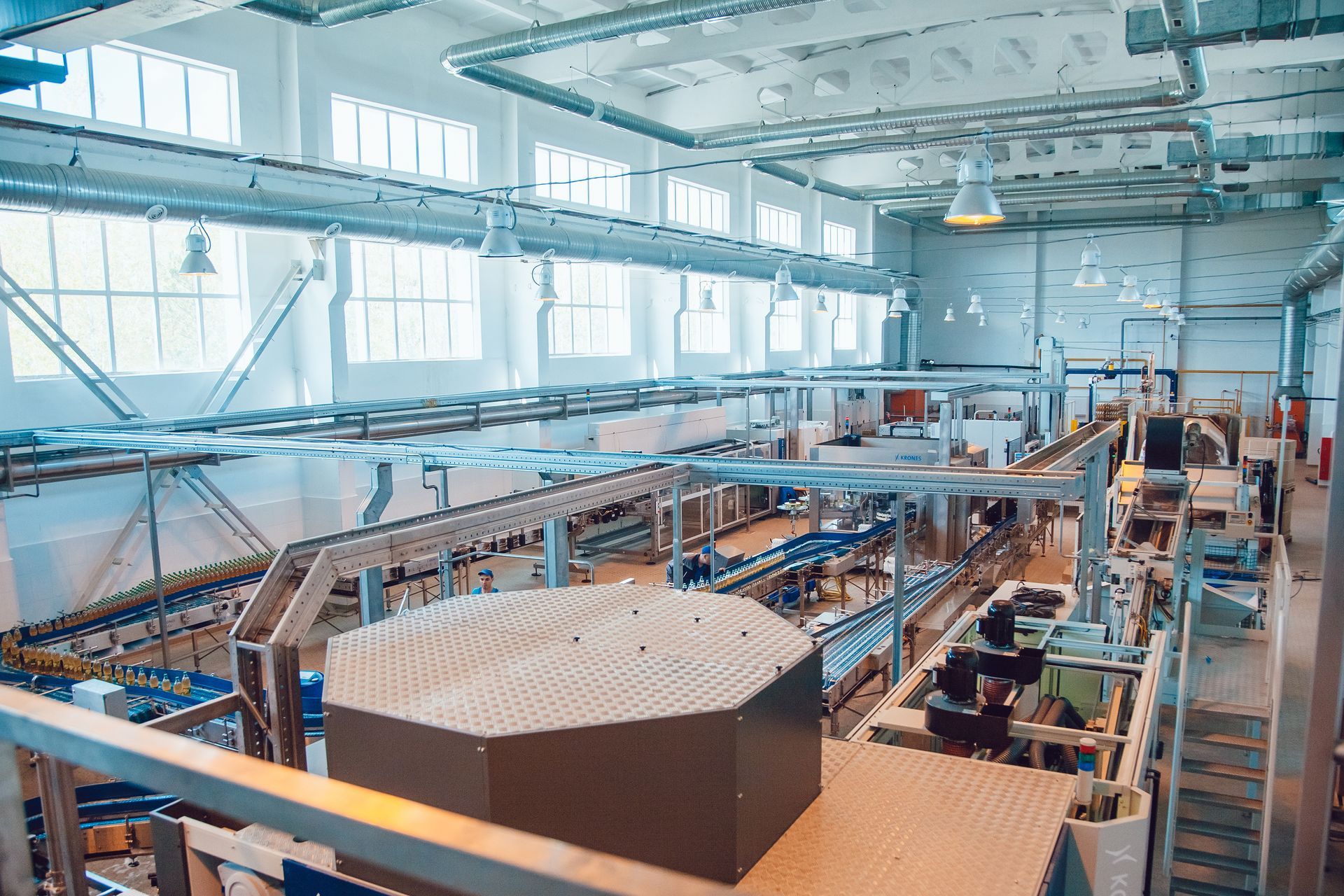 Factory interior with conveyor belts, overhead lighting, and large container.