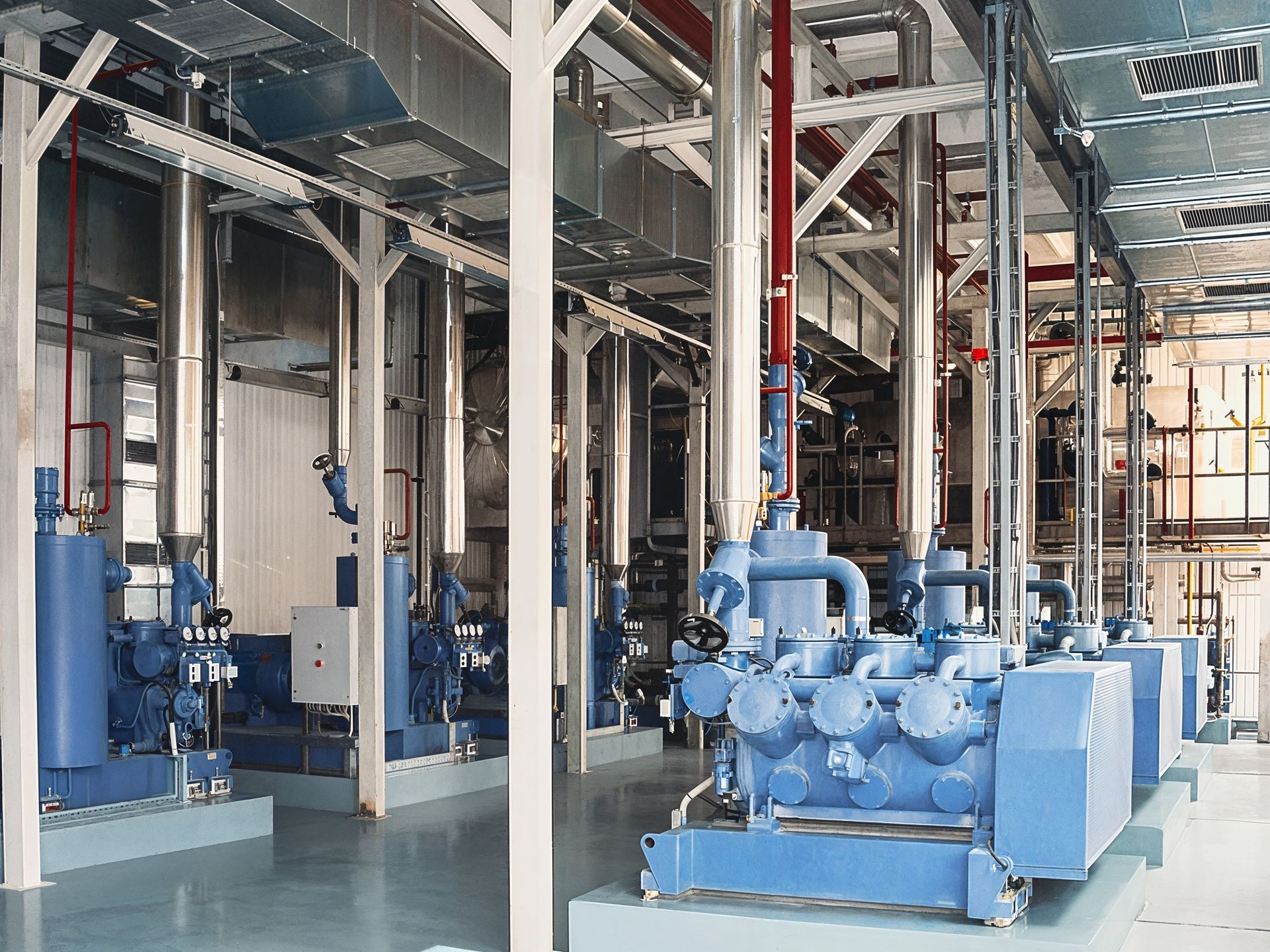 Blue industrial refrigeration equipment inside a clean building with pipes and supports.