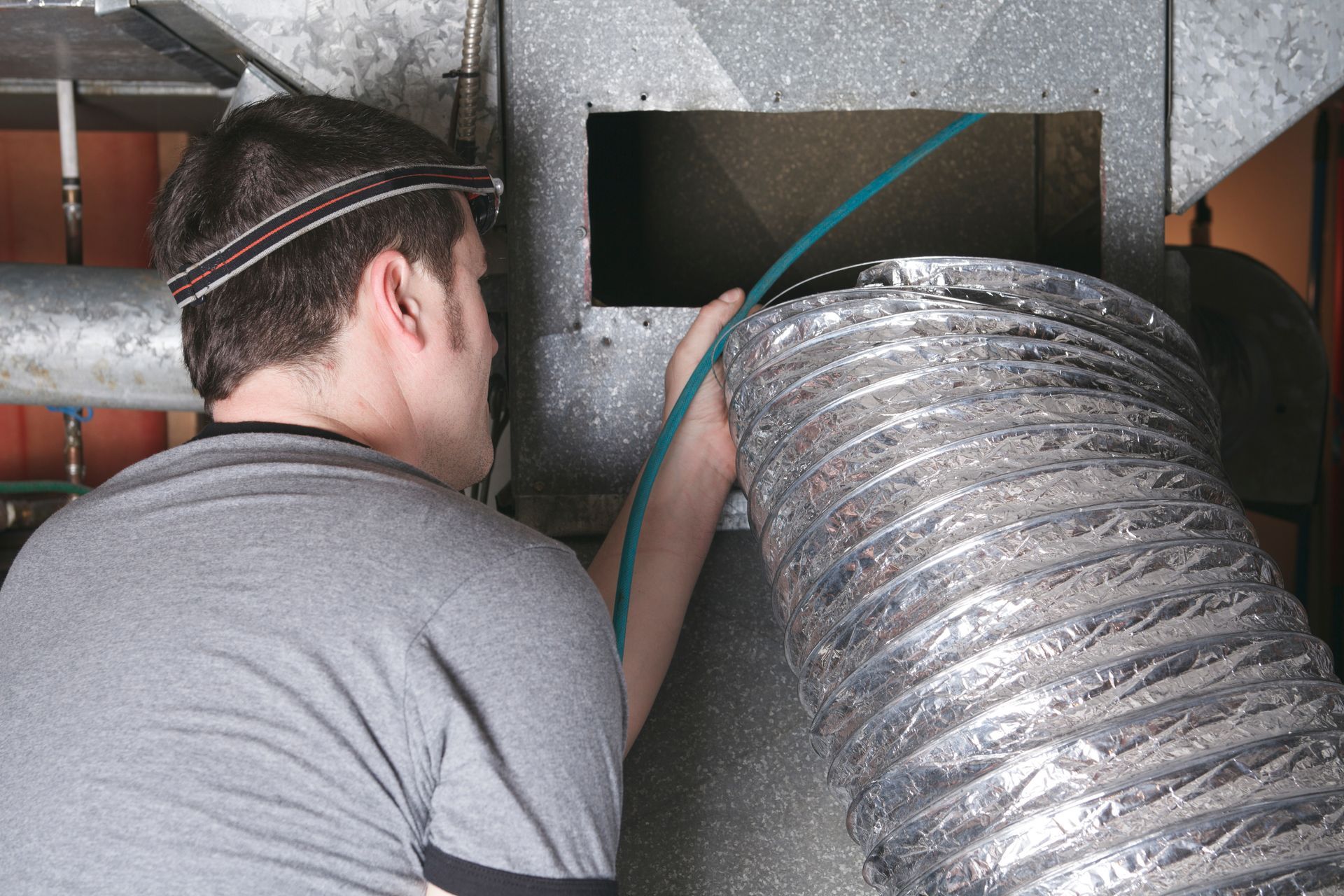 HVAC technician attaching flexible duct hose to metal vent opening indoors HVAC technician attaching flexible duct hose to metal vent opening indoors