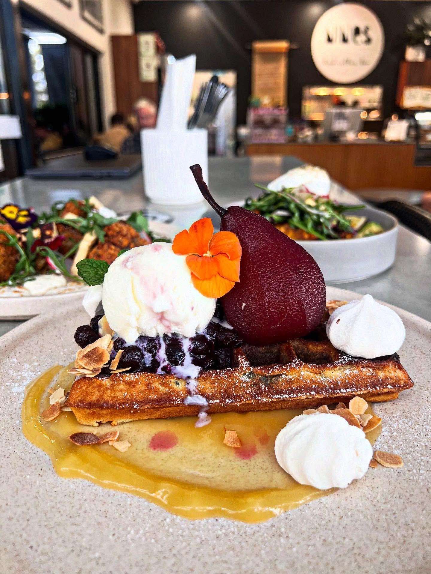 A close up of a plate of food with ice cream and a pear on a table.