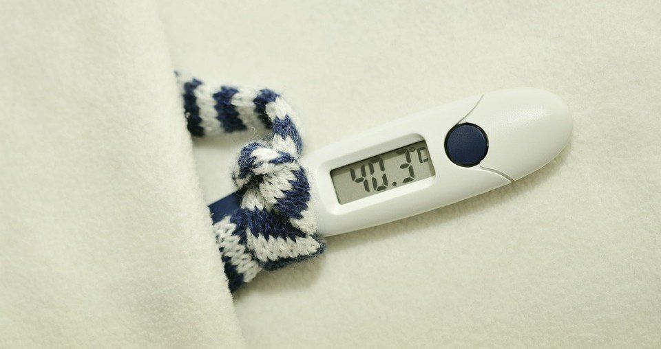 Digital thermometer showing 40.3°C beside a striped cloth strap