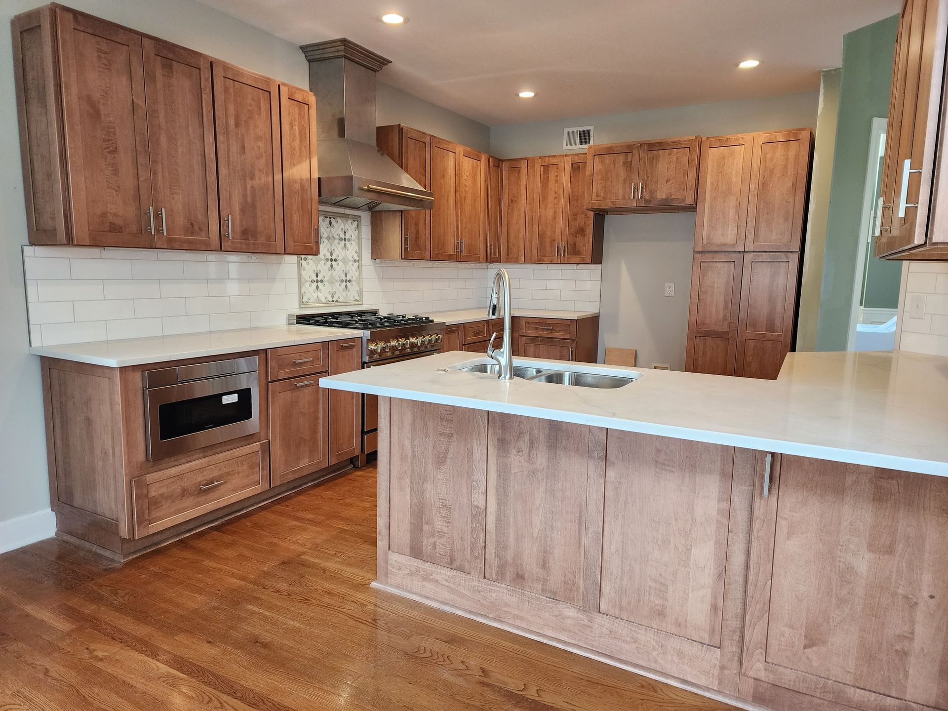 Kitchen with wood cabinets, white countertops, stainless steel appliances, and wood floor.