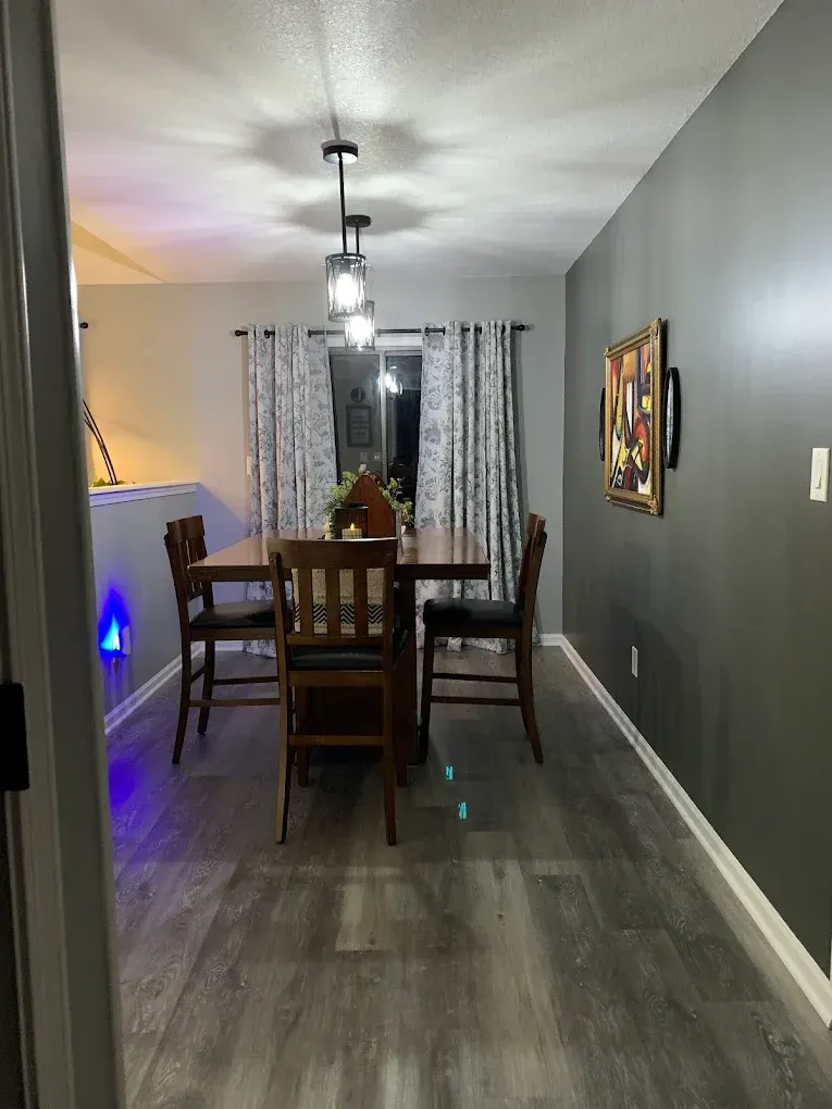 Dining room with dark wood table, chairs, gray walls, and patterned curtains.