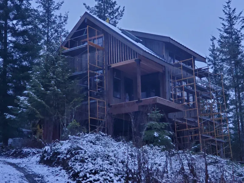 A house is being built in the middle of a snowy forest.