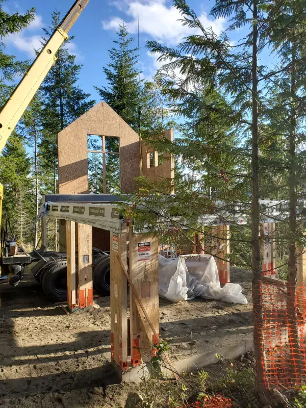A house is being built in the woods with a crane in the background
