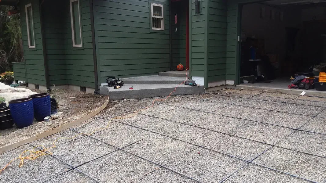 A gravel driveway in front of a green house.
