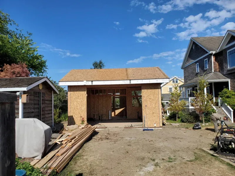 A garage is being built in the backyard of a house.