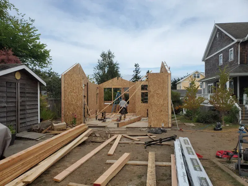 A man is standing in front of a house under construction.