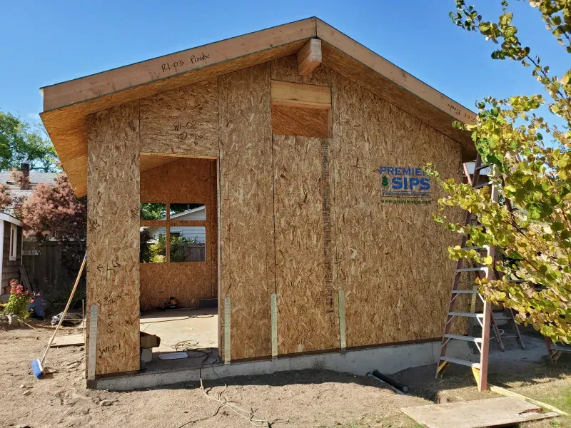 A small wooden house is being built in a backyard.