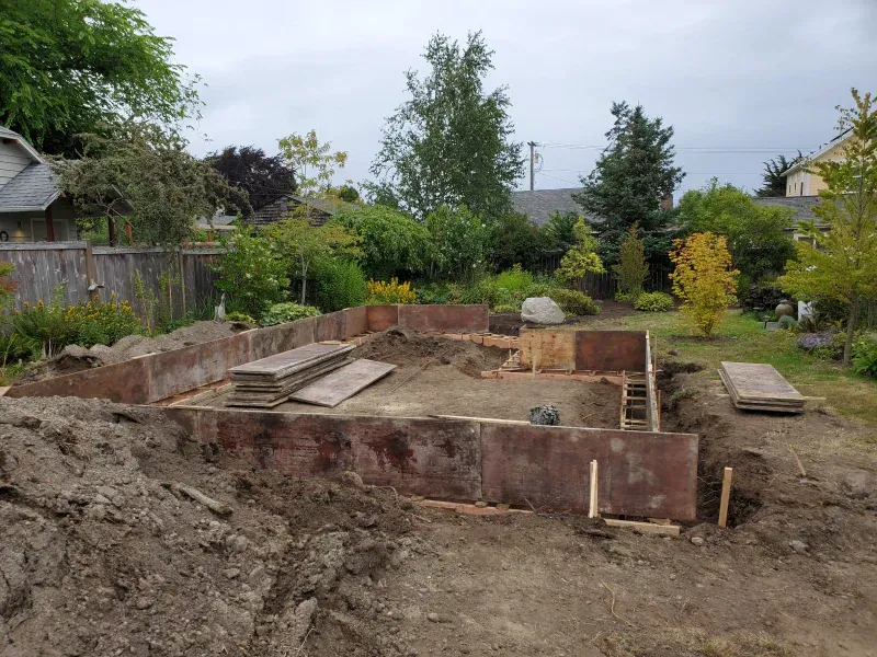 A large pile of dirt is sitting in the middle of a backyard.