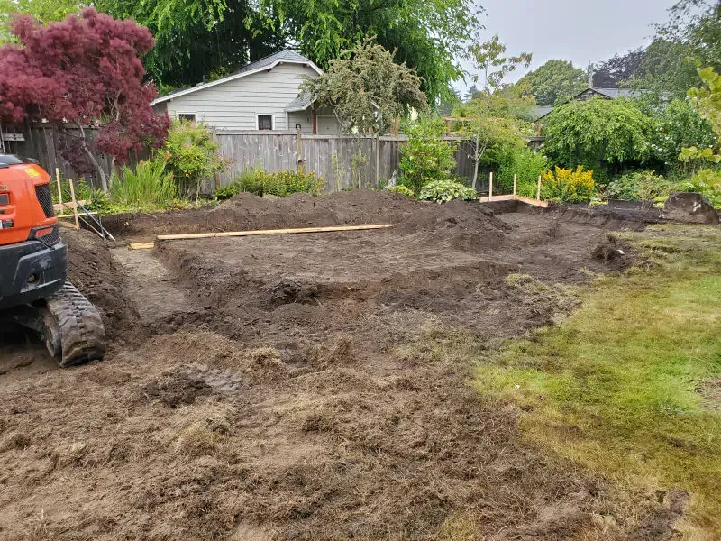 A backyard with a lot of dirt and a house in the background.